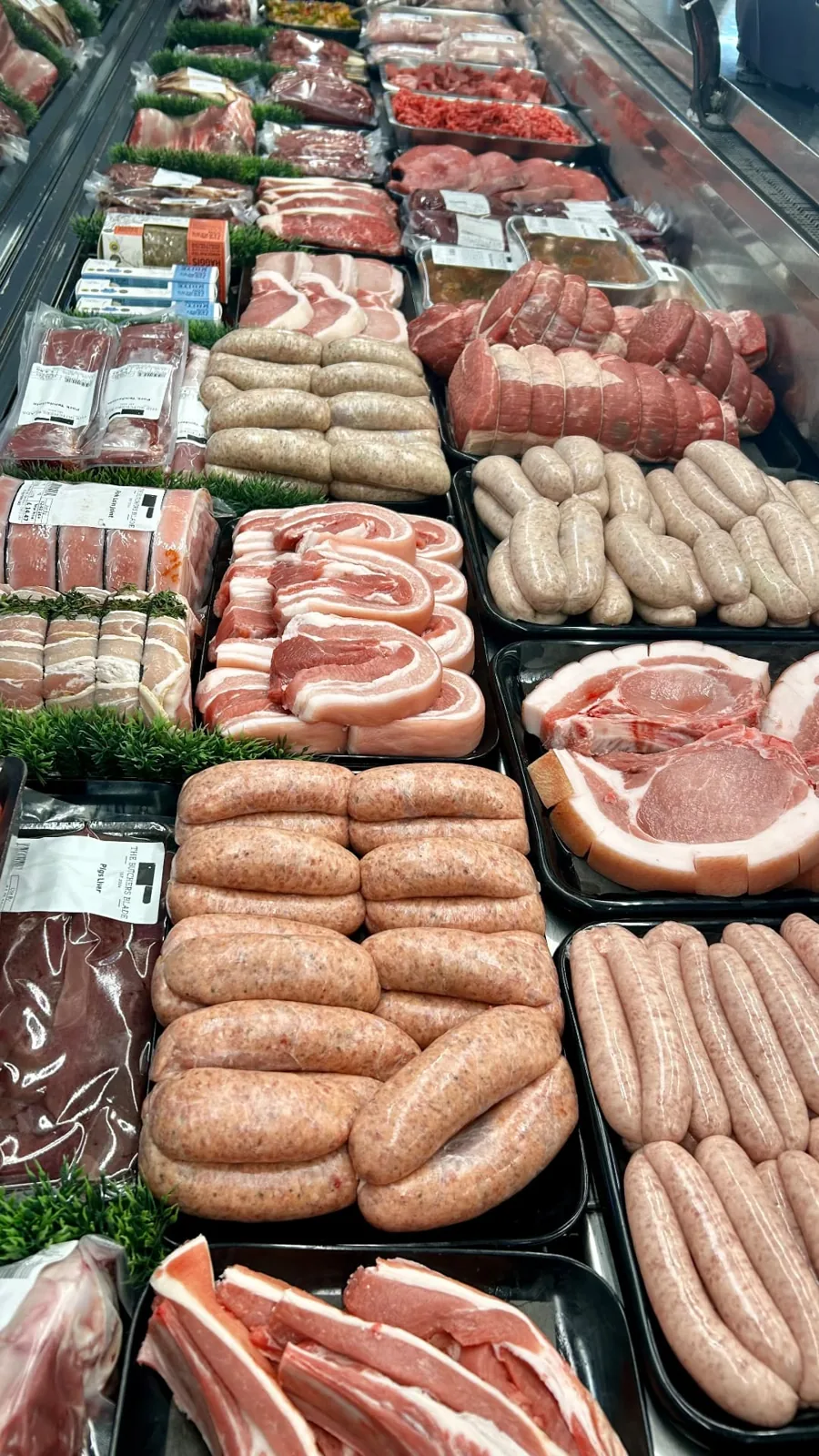 Rows of gluten-free sausages and prepared meat portions along the butcher’s counter