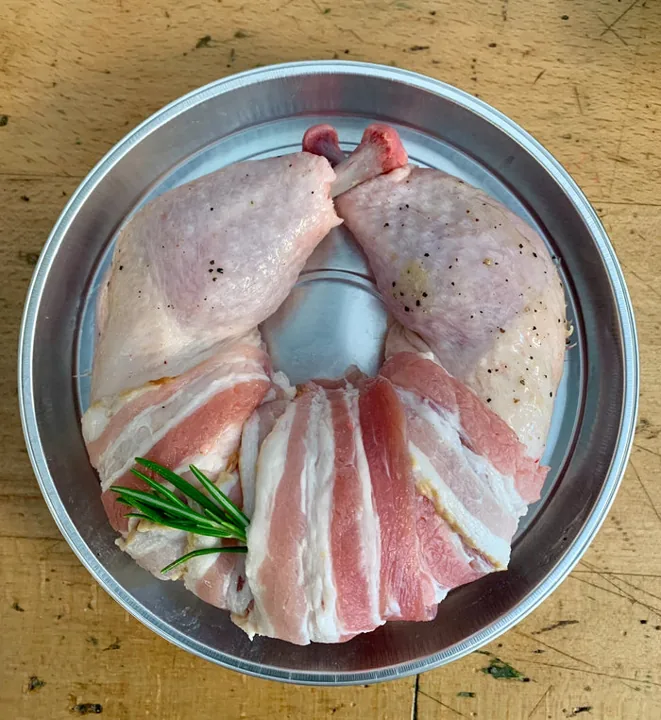 Chicken legs wrapped in bacon, prepared by the butcher, on a tray