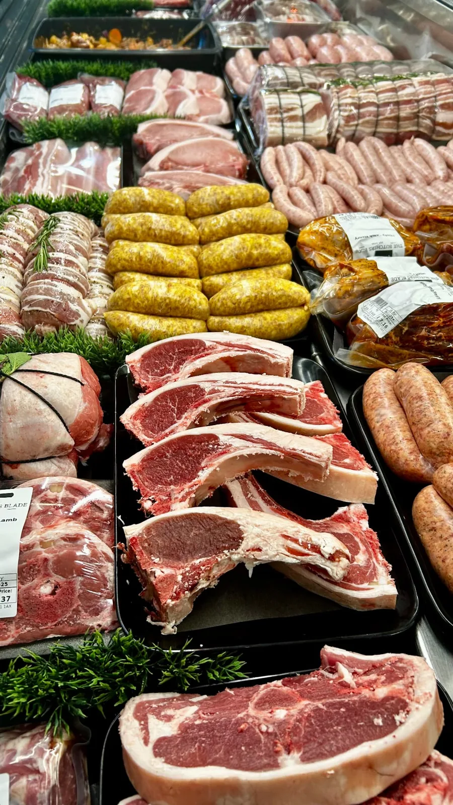 Bone-in beef steaks beside sausages in The Butchers Blade counter